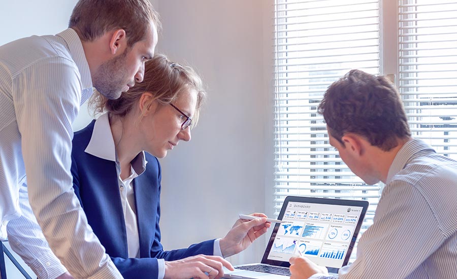 An image of three people reading data on a screen​